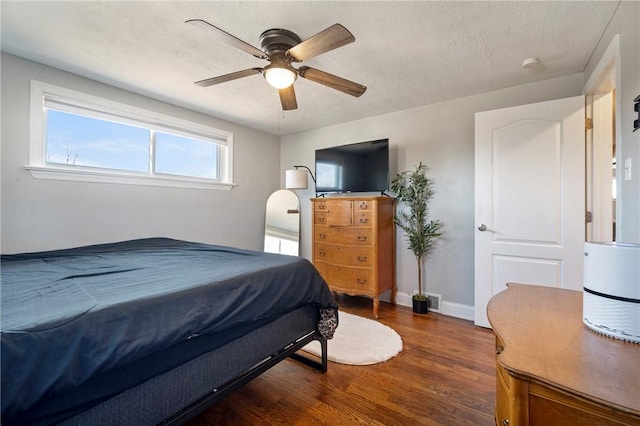 bedroom featuring a textured ceiling, a ceiling fan, baseboards, and wood finished floors