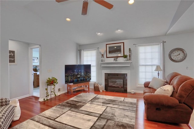 living room with visible vents, a fireplace with flush hearth, a ceiling fan, and wood finished floors