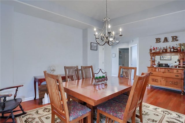 dining space with a chandelier, baseboards, and wood finished floors