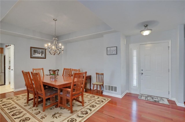 dining area with baseboards, light wood-style floors, visible vents, and a chandelier