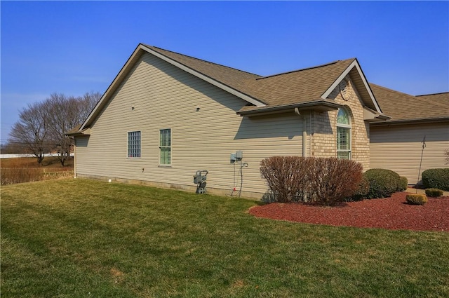 view of side of property with a lawn and roof with shingles