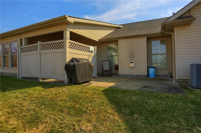 view of side of property with central AC unit, a patio area, a lawn, and roof with shingles