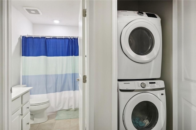 laundry area featuring tile patterned flooring, laundry area, visible vents, and stacked washer / drying machine