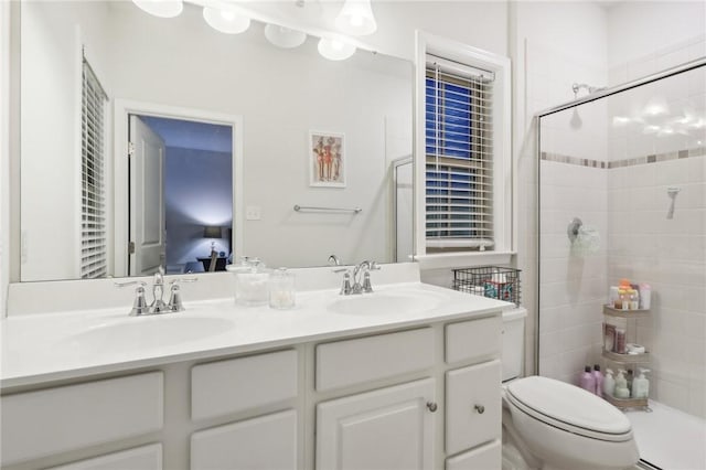 ensuite bathroom with double vanity, toilet, tiled shower, and a sink