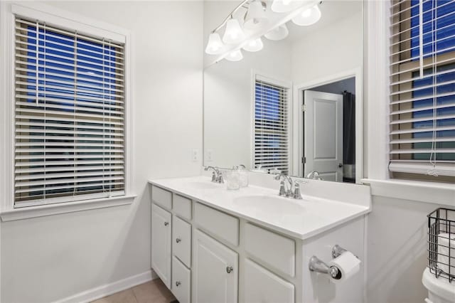 bathroom featuring tile patterned flooring, double vanity, baseboards, and a sink