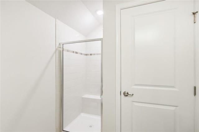 bathroom with a shower stall and vaulted ceiling