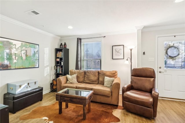 living area featuring baseboards, visible vents, light wood-type flooring, and ornamental molding