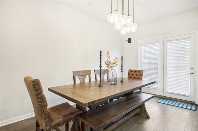 dining room featuring a notable chandelier, baseboards, and wood finished floors