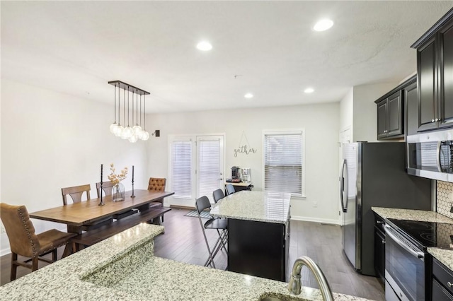 kitchen featuring stainless steel microwave, dark wood-type flooring, light stone countertops, recessed lighting, and electric range