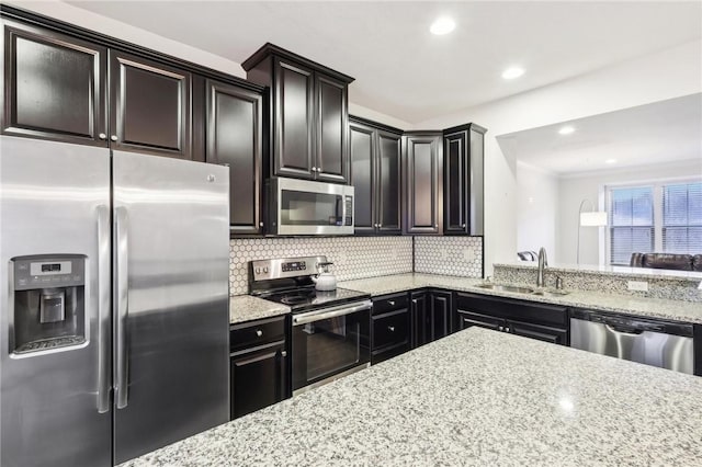 kitchen with light stone countertops, recessed lighting, a sink, decorative backsplash, and appliances with stainless steel finishes