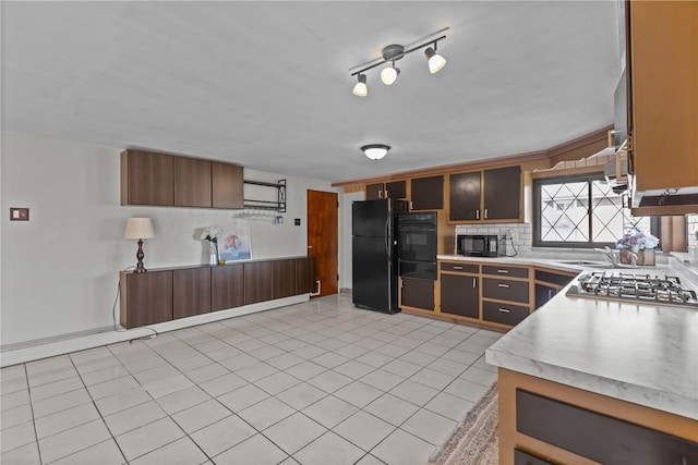 kitchen with black appliances, light tile patterned flooring, light countertops, and tasteful backsplash