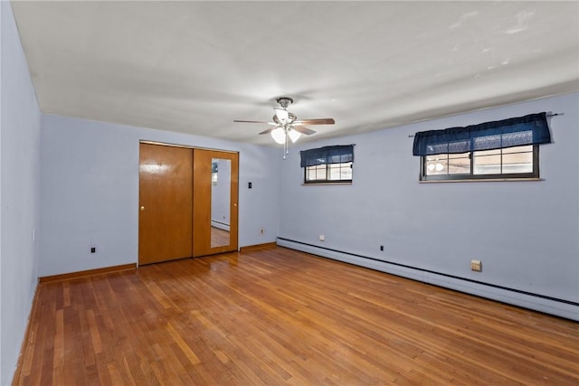 empty room featuring a baseboard heating unit, hardwood / wood-style flooring, baseboards, and ceiling fan