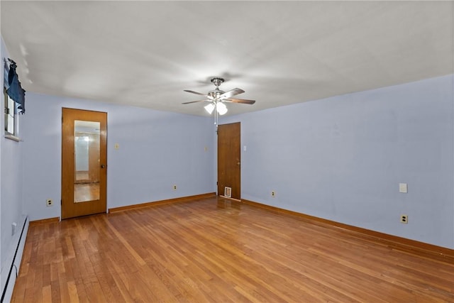 unfurnished room featuring a baseboard heating unit, light wood-style floors, baseboards, and ceiling fan