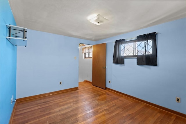 empty room with baseboards and wood-type flooring