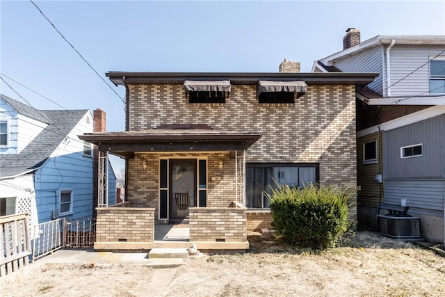 view of front of home featuring fence, cooling unit, covered porch, brick siding, and a chimney