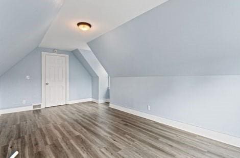 additional living space featuring lofted ceiling, wood finished floors, baseboards, and visible vents