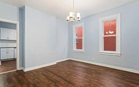 unfurnished dining area with baseboards, dark wood-type flooring, and an inviting chandelier