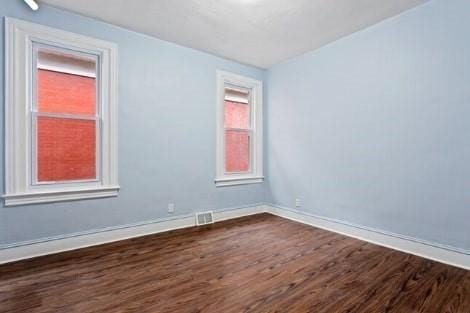 empty room with visible vents, baseboards, and dark wood-style flooring