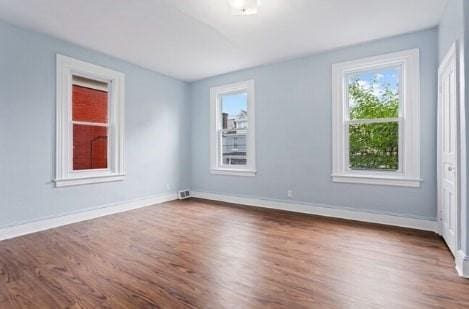 spare room featuring dark wood-style floors and baseboards