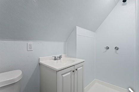 bathroom featuring a shower, lofted ceiling, toilet, and vanity