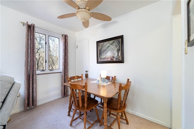 dining space with baseboards, light carpet, and a ceiling fan