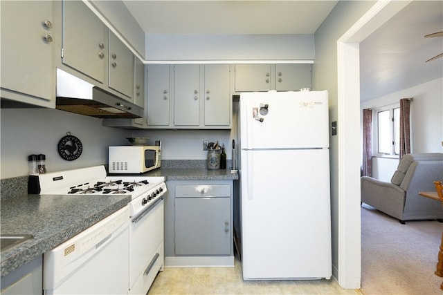 kitchen with white appliances, dark countertops, gray cabinets, and under cabinet range hood