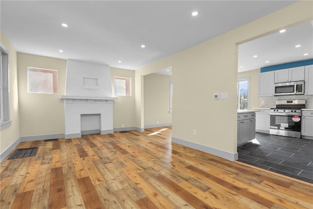 unfurnished living room featuring baseboards, a healthy amount of sunlight, and hardwood / wood-style flooring