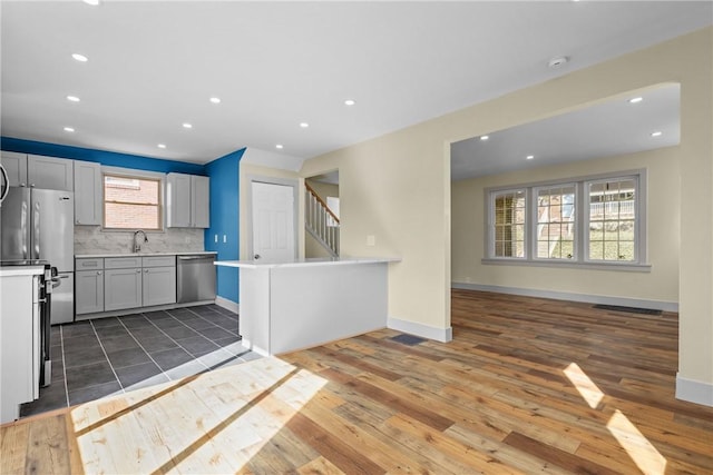 kitchen featuring backsplash, baseboards, light countertops, appliances with stainless steel finishes, and a sink