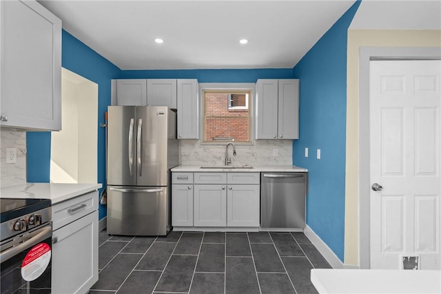 kitchen featuring tasteful backsplash, dark tile patterned floors, light countertops, stainless steel appliances, and a sink