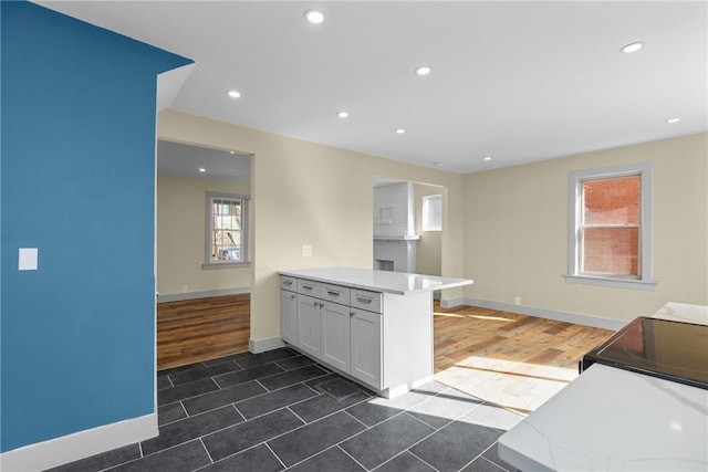 kitchen with recessed lighting, a peninsula, wood finished floors, and white cabinetry