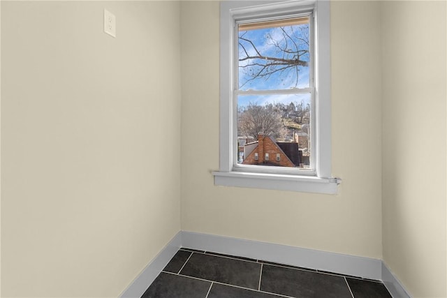 spare room featuring dark tile patterned floors and baseboards