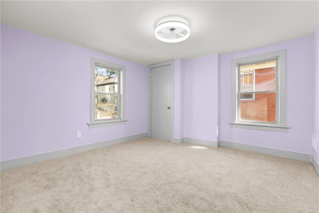 unfurnished room featuring light carpet and baseboards