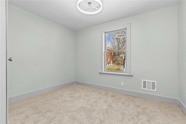 spare room featuring carpet, visible vents, and baseboards