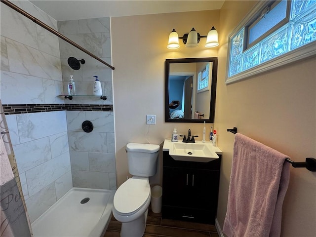 bathroom with vanity, toilet, and tiled shower