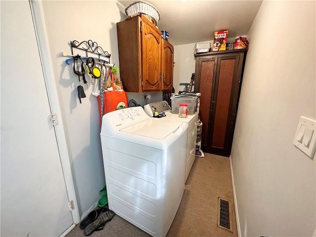 laundry area with visible vents, baseboards, washing machine and dryer, water heater, and cabinet space