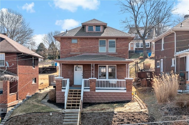 view of front of house featuring brick siding, stairway, a porch, and a shingled roof