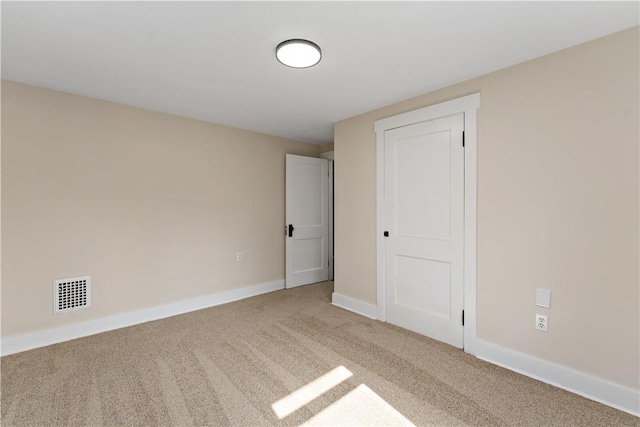 empty room featuring carpet, visible vents, and baseboards