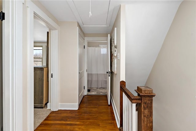 hallway with baseboards, attic access, and dark wood-style floors