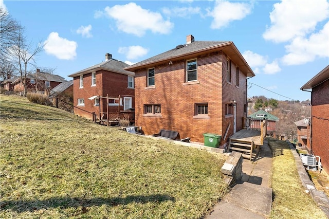 rear view of property featuring a lawn, brick siding, and a chimney