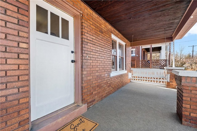 property entrance with brick siding and covered porch