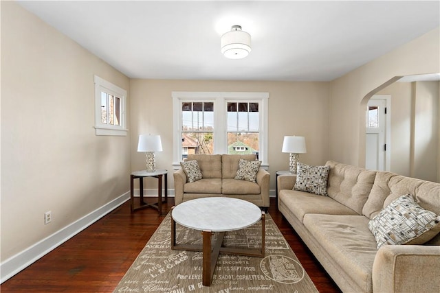 living room featuring baseboards, arched walkways, and dark wood-style flooring