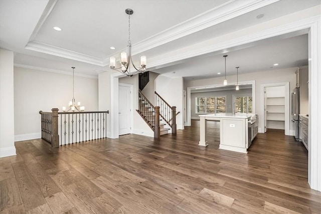 kitchen featuring dark wood-style floors, an inviting chandelier, light countertops, crown molding, and a kitchen breakfast bar