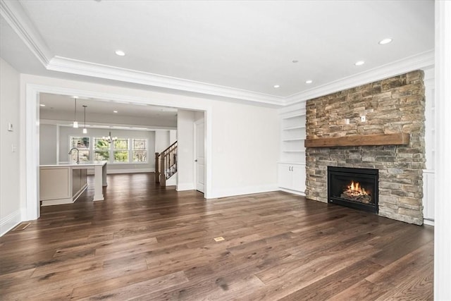 unfurnished living room with stairway, built in shelves, dark wood-style flooring, and ornamental molding