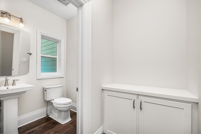 bathroom featuring wood finished floors, visible vents, baseboards, a sink, and toilet