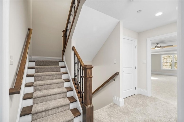 stairs with a ceiling fan, carpet, and baseboards