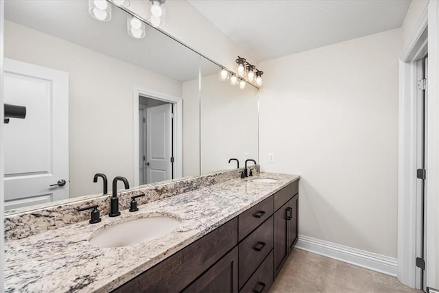 bathroom with a sink, baseboards, double vanity, and tile patterned floors