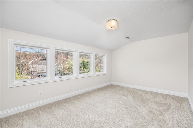 carpeted empty room featuring visible vents, baseboards, and vaulted ceiling