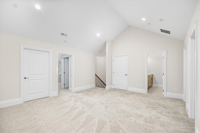 unfurnished bedroom featuring lofted ceiling, light colored carpet, visible vents, and baseboards