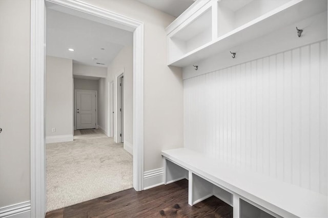 mudroom with dark carpet, baseboards, and dark wood-style flooring