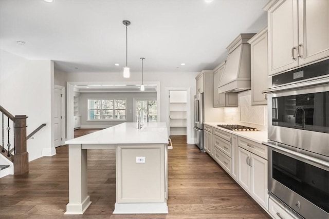 kitchen featuring custom range hood, a sink, stainless steel appliances, light countertops, and dark wood-style flooring